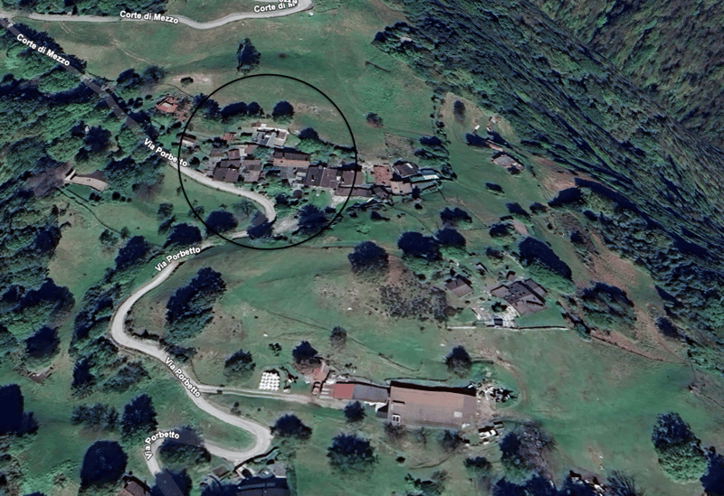Mountainous area with several residential buildings, circular circle highlighting a group of buildings