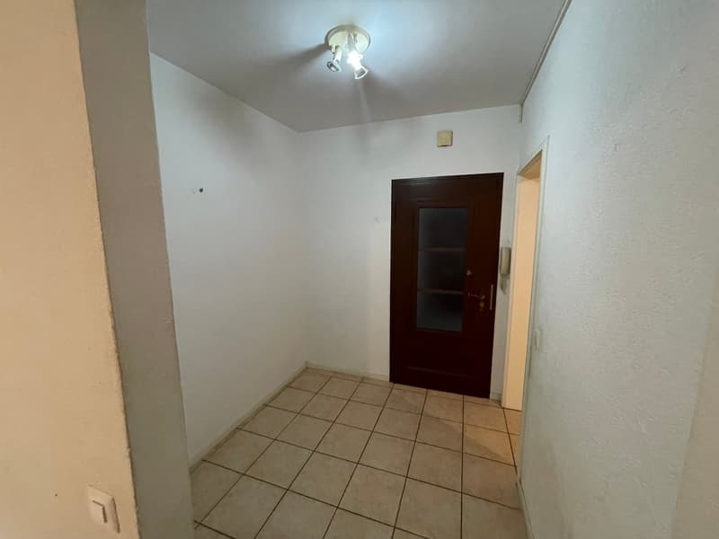Empty room, tiled floor, white walls, ceiling light, door, small window