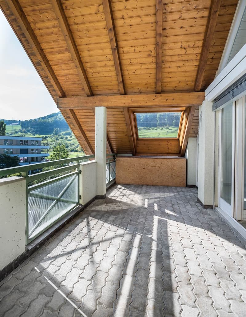 Balcony with a wooden ceiling, hexagonal tiles on the floor, and a view of the outdoors.