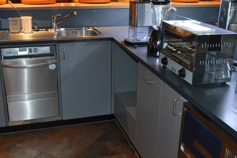 Modern kitchen with stainless steel appliances, including a dishwasher and washing machine, built-in cabinets, and a sink with a faucet.