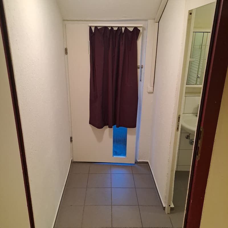 white walls, closed door, tiled floor, small window on door