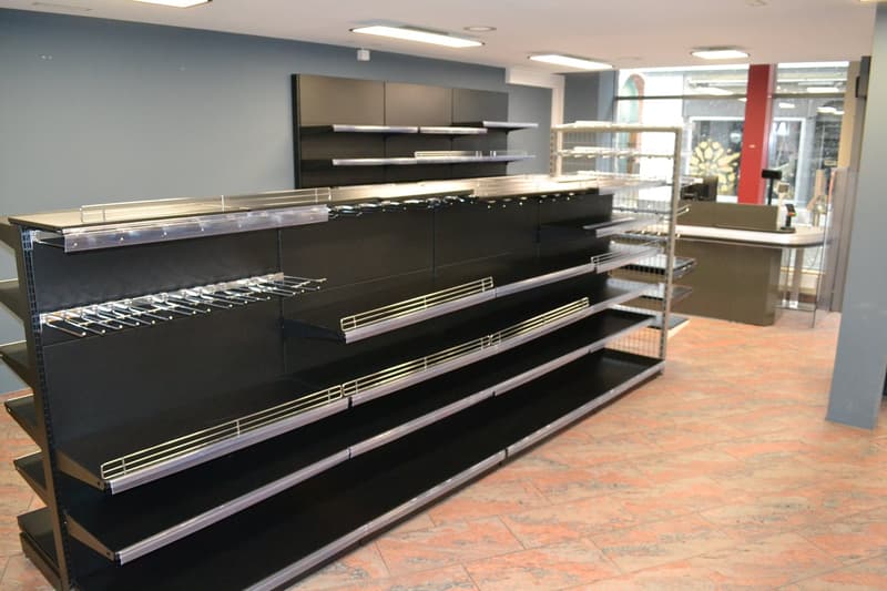Store with black shelves, stainless steel baskets, glass cabinets, and red tiled floor.