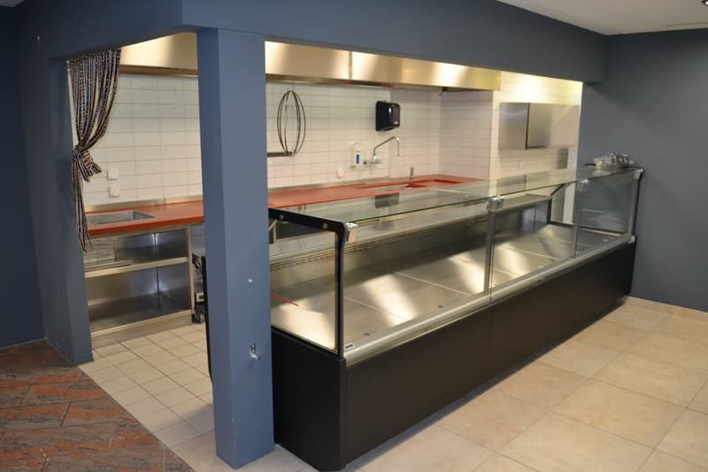 commercial kitchen area with counter, sink, and large glass display case