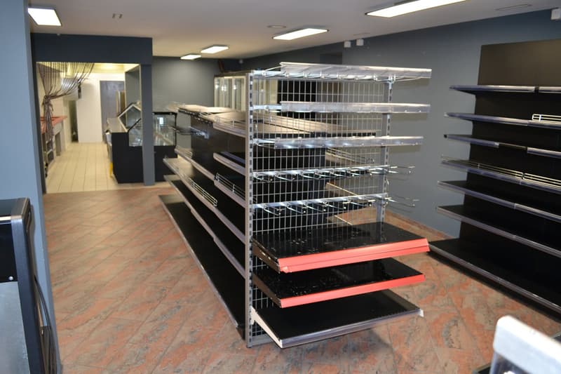 Empty shop with stainless steel shelving, tiled floor, recessed lighting, open entrance