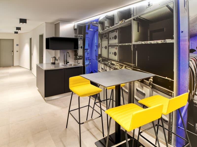 white tiled floor, gray table, yellow chairs, stainless steel sink, gas stove, countertop, yellow chairs