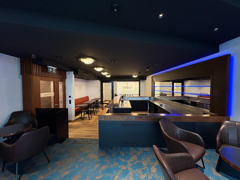 bar area with tables and chairs, wooden floor, blue ceiling lights, blue illuminated bar