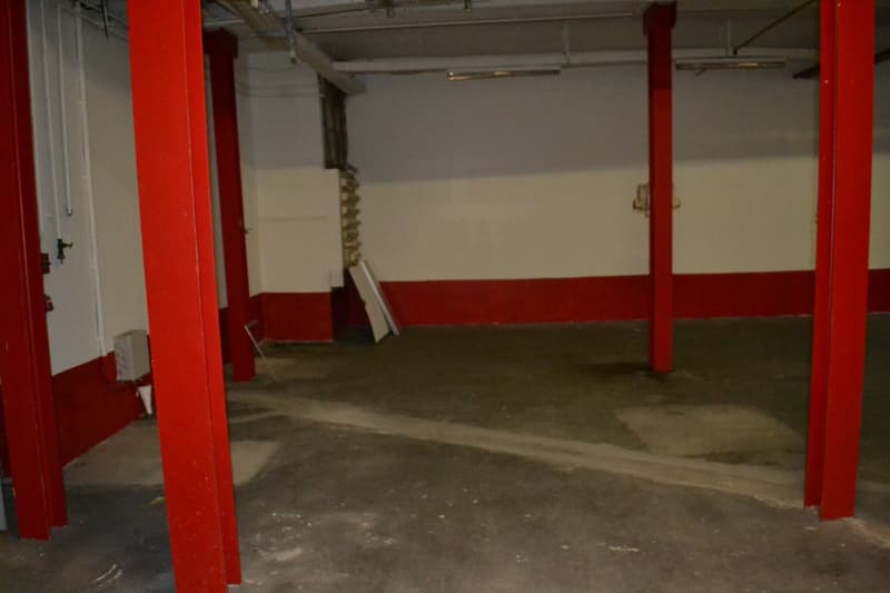 Empty room, concrete floor, red pillars, white walls, ceiling lights