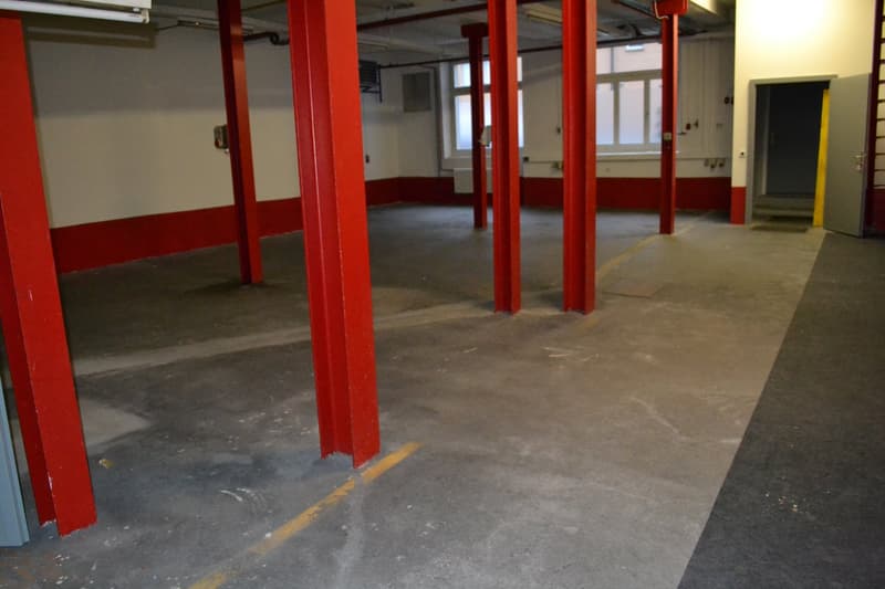 Empty parking lot with red pillars, concrete floor, windows, and doors
