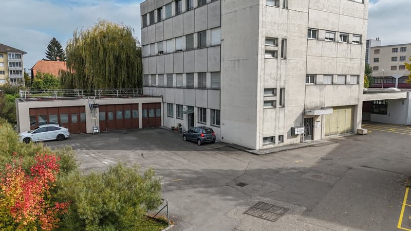 concrete building with multiple floors, multiple garages in front