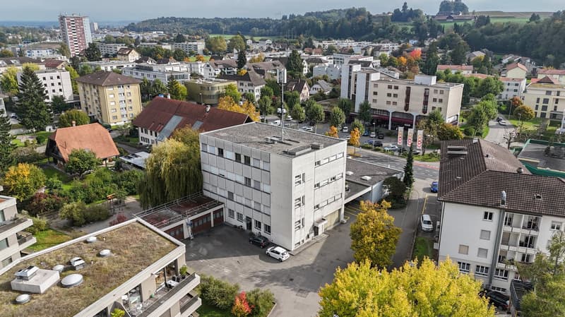 apartment buildings, a road, a building with a garage, and several cars parked