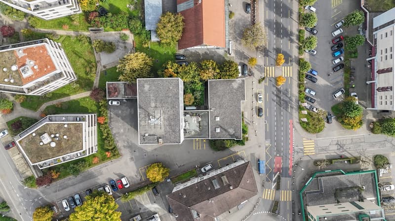 Aerial view of several residential buildings with parking spaces and trees, with an intersection