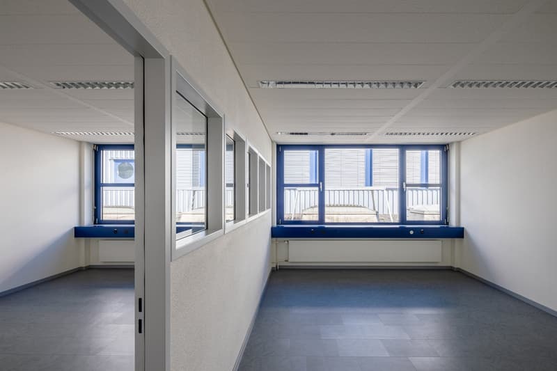 White walls, ceiling, windows with blue frames, tiled floor, radiators, open doorway, blue balcony ledge