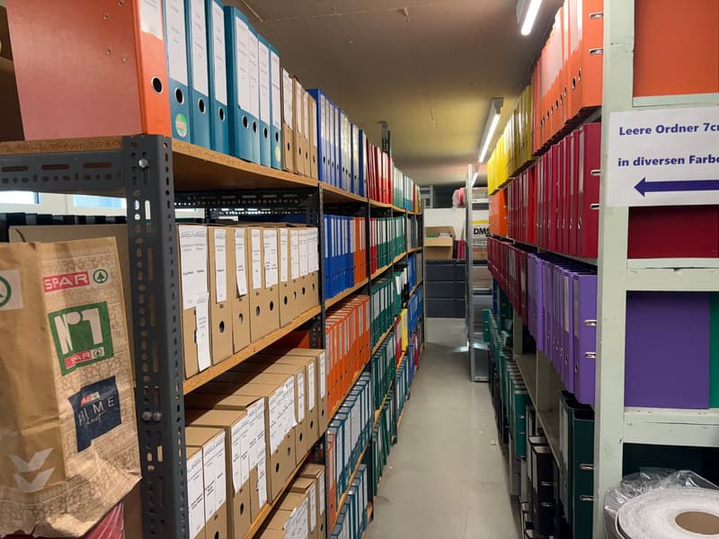 Storage room filled with neatly arranged file cabinets, categorized by color, with a central walkway for easy access