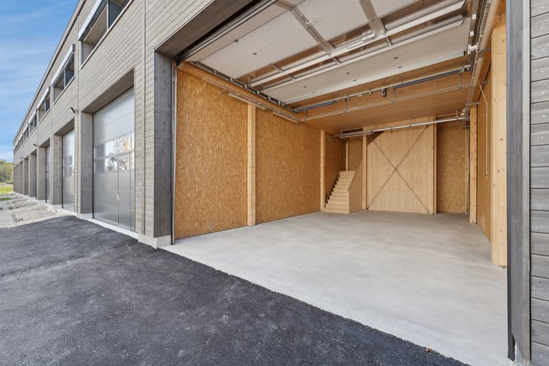 Empty garage with wooden walls, concrete floor, staircase, and multiple doors