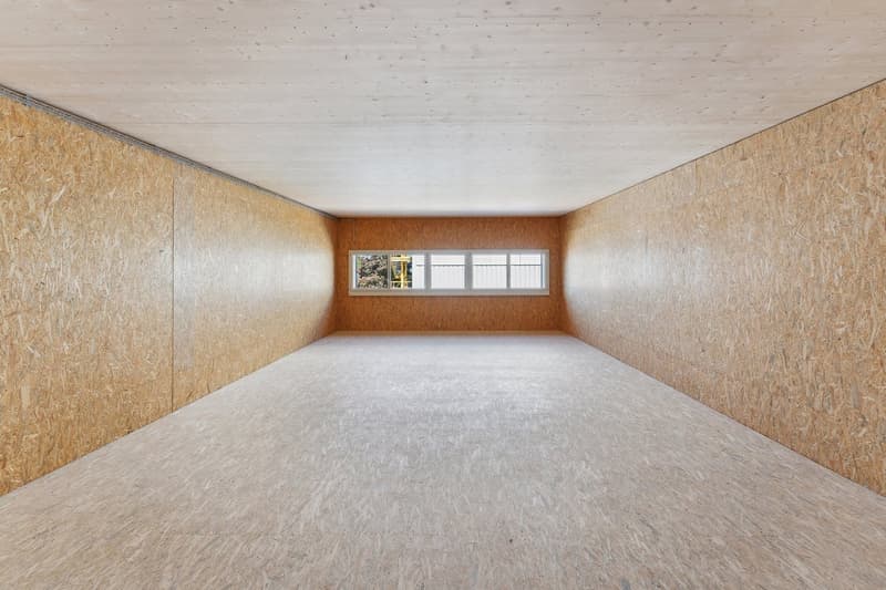 Empty room with wooden panels on the walls and ceiling, white floor, and a window.