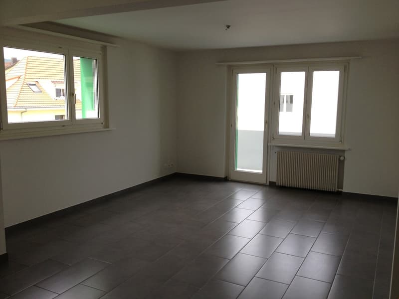 empty room, white walls, black tiles, two large windows, sliding door