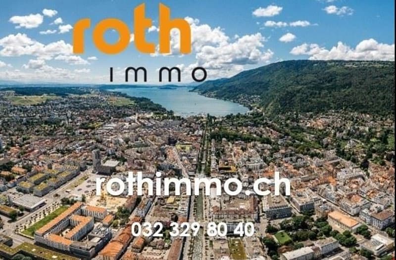 An aerial view of a town with buildings and a river, mountains in the background