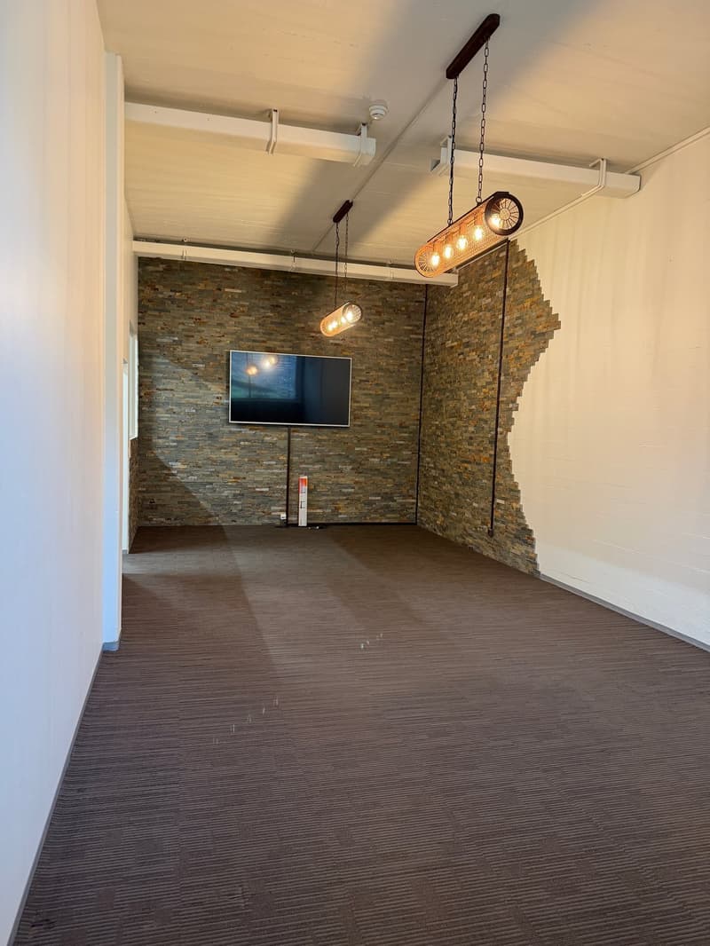 empty room with brick wall, mounted TV, hanging lamps, and white and brown floor