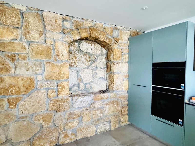a kitchen with a stone wall and a double oven