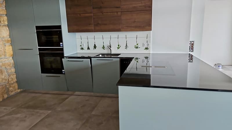 Modern kitchen with white cabinets, gray walls, black countertop, black oven, and double sinks