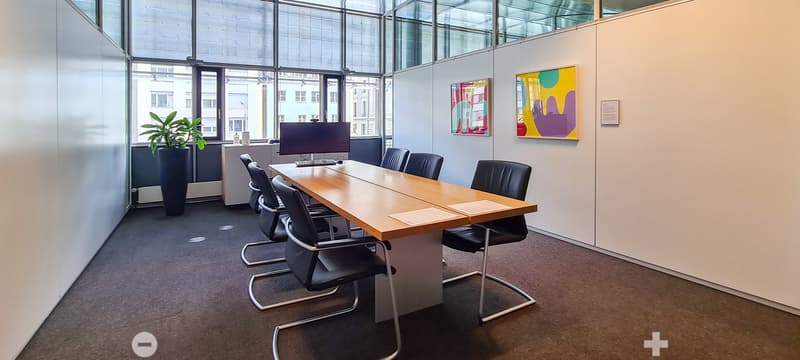 modern conference room, long wooden table, black chairs, monitor, potted plant, glass walls, paintings