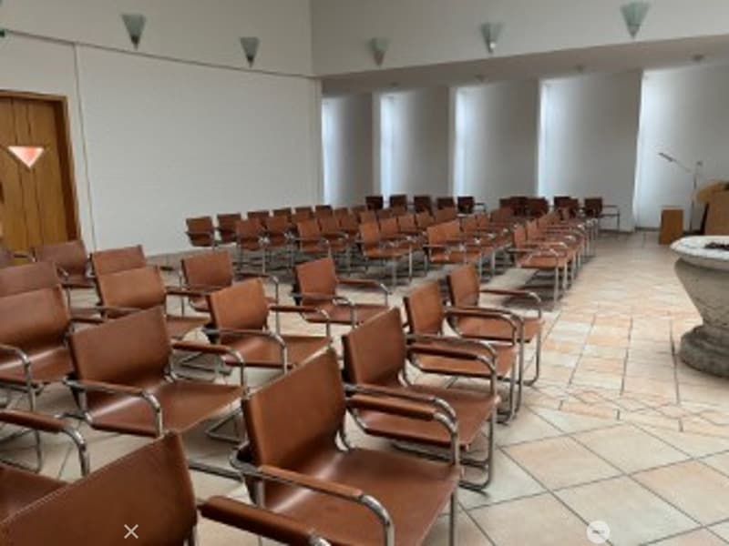 empty room, rows of brown leather chairs, white walls, wooden door, tiled floor