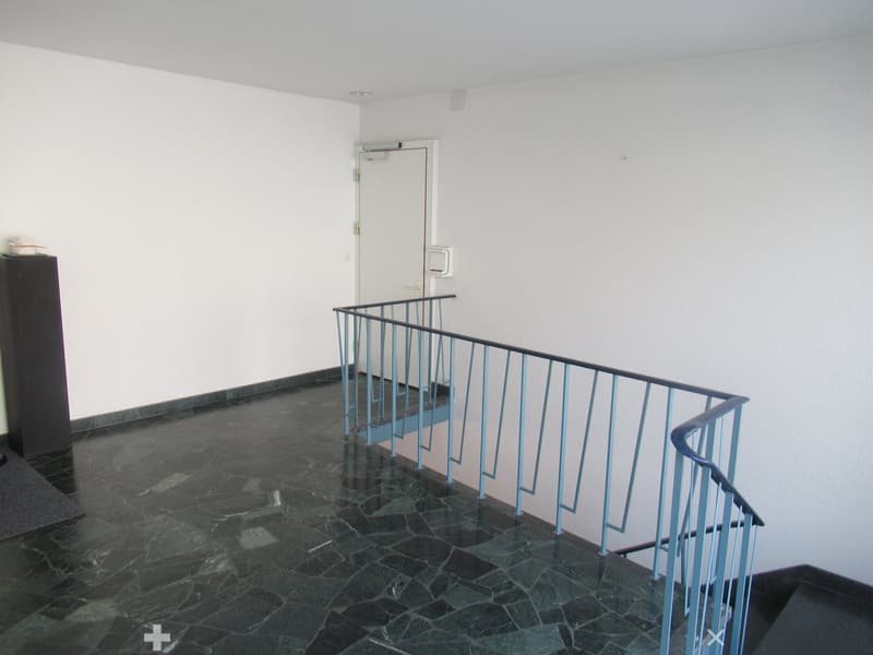 minimalist interior with black marble flooring, white walls, modern staircase with blue railing, open door