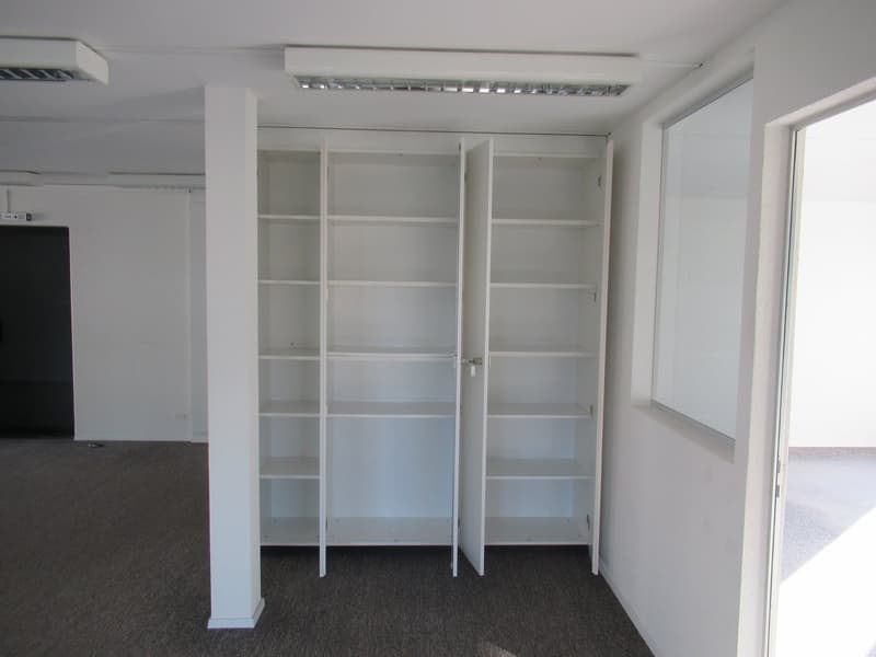 A room with a built-in wardrobe, white interior, and carpeted floor.