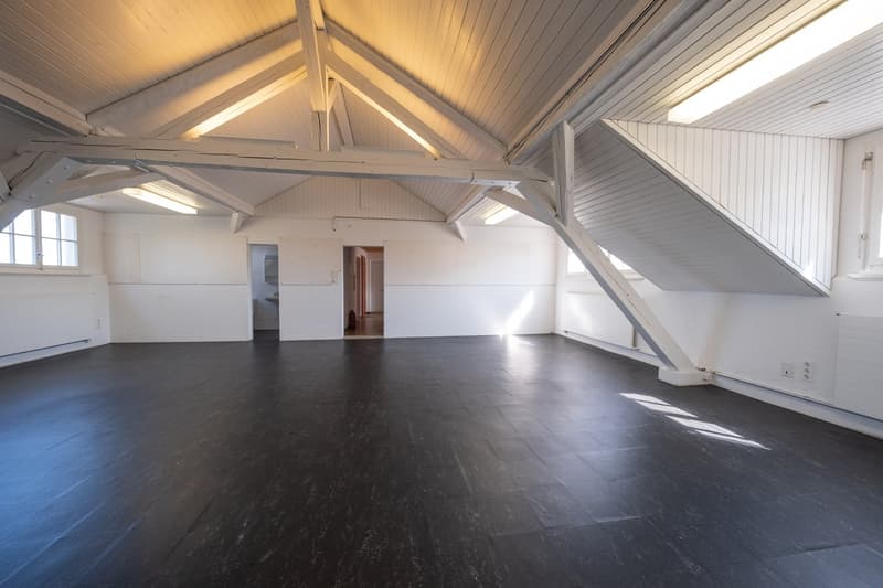 empty room with white ceiling beams, black floor, windows