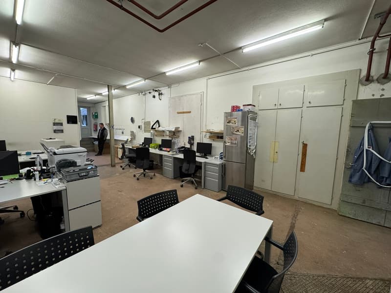 Office space with white desks, office chairs, computer equipment, cabinets, and refrigerator.