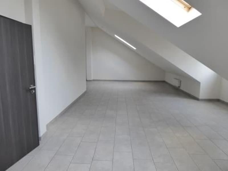 Attic room with white walls, gray tile flooring, and a slanted ceiling with a skylight window.