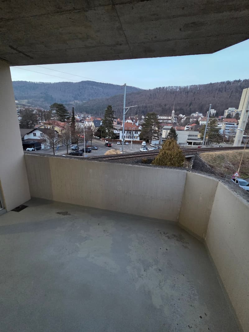 exposed concrete flooring, concrete balcony railing, view of a town with mountains in the distance