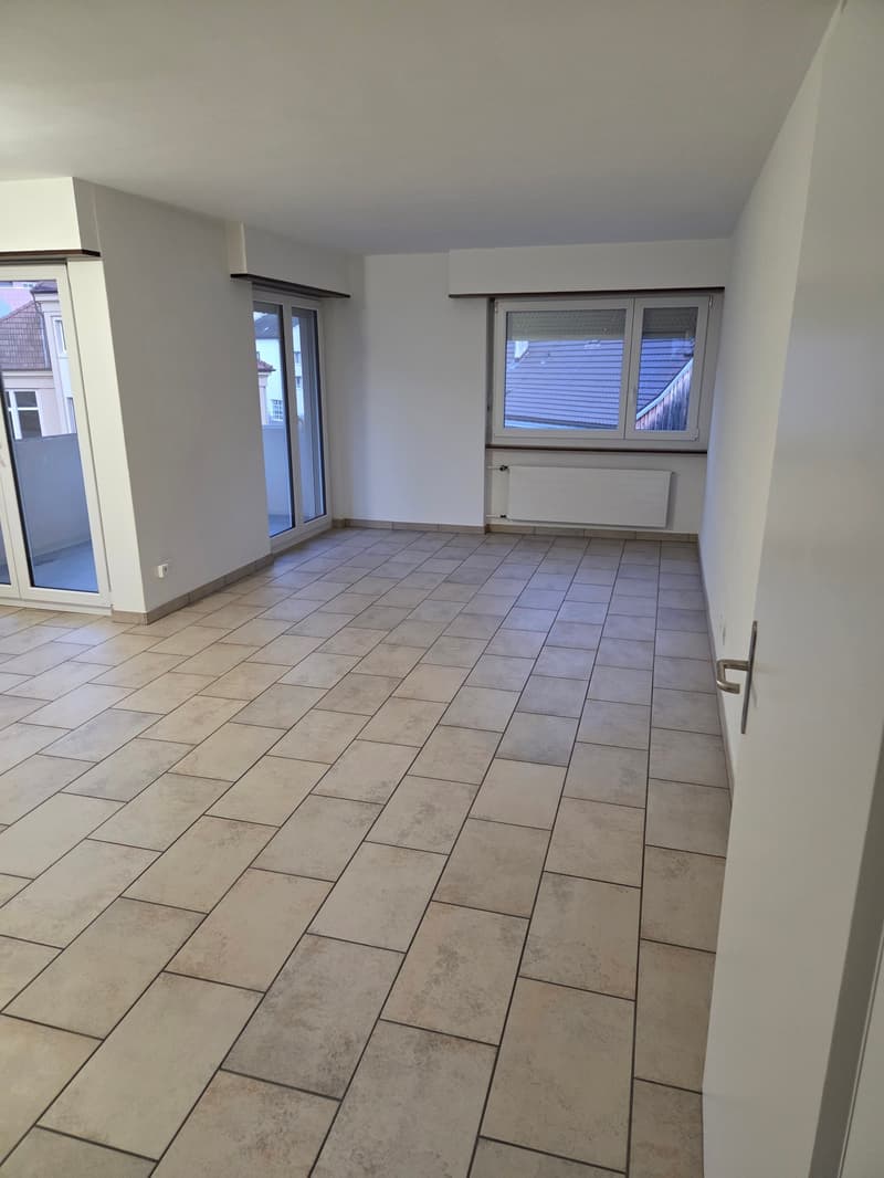 Empty room with tiled floor, large windows, balcony on the left