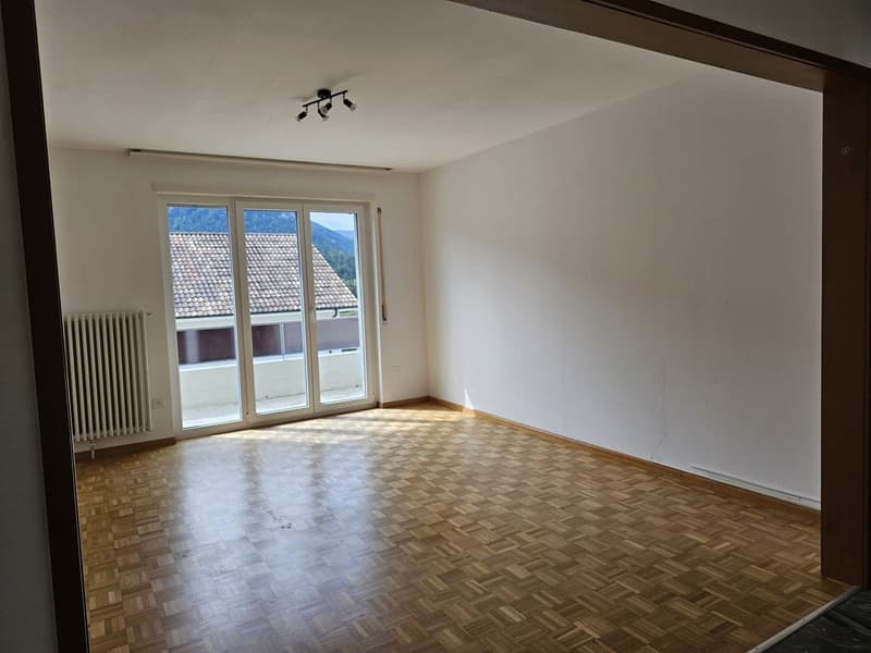 empty room, wooden parquet flooring, white walls, large sliding glass door to balcony, white radiator
