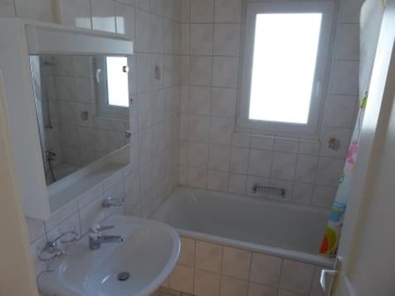 tiled walls, white bathtub, sink, mirror, window