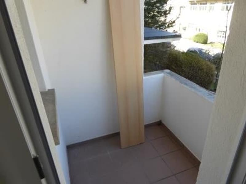 A balcony with tiled floor and white walls, empty.