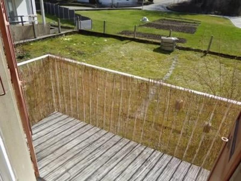 Wooden deck with fence, grassy field, white house in the background