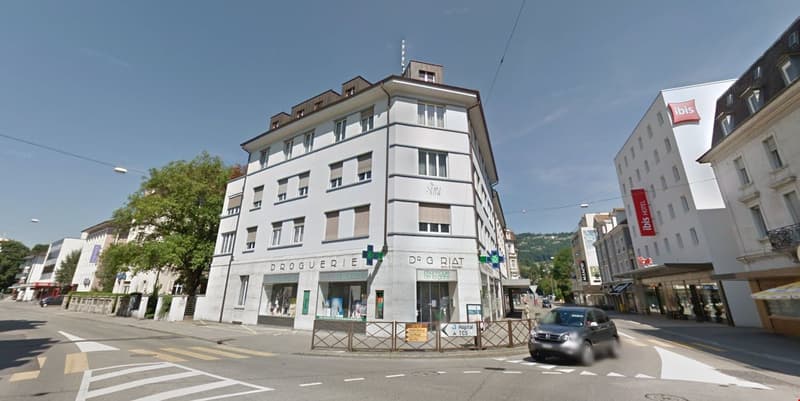 5 story building, multiple balconies, shops on the ground floor, pharmacy and hospital