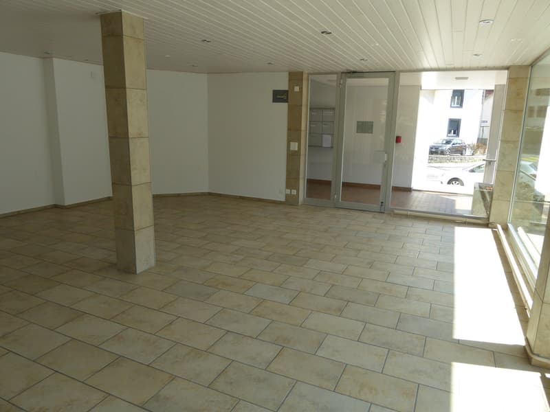 spacious entrance hall with tile flooring, white walls, sliding glass doors, small column, mailboxes, windows
