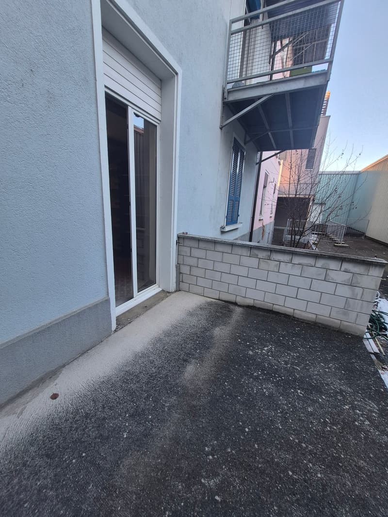 white building exterior, balcony with metal railings, concrete pathway