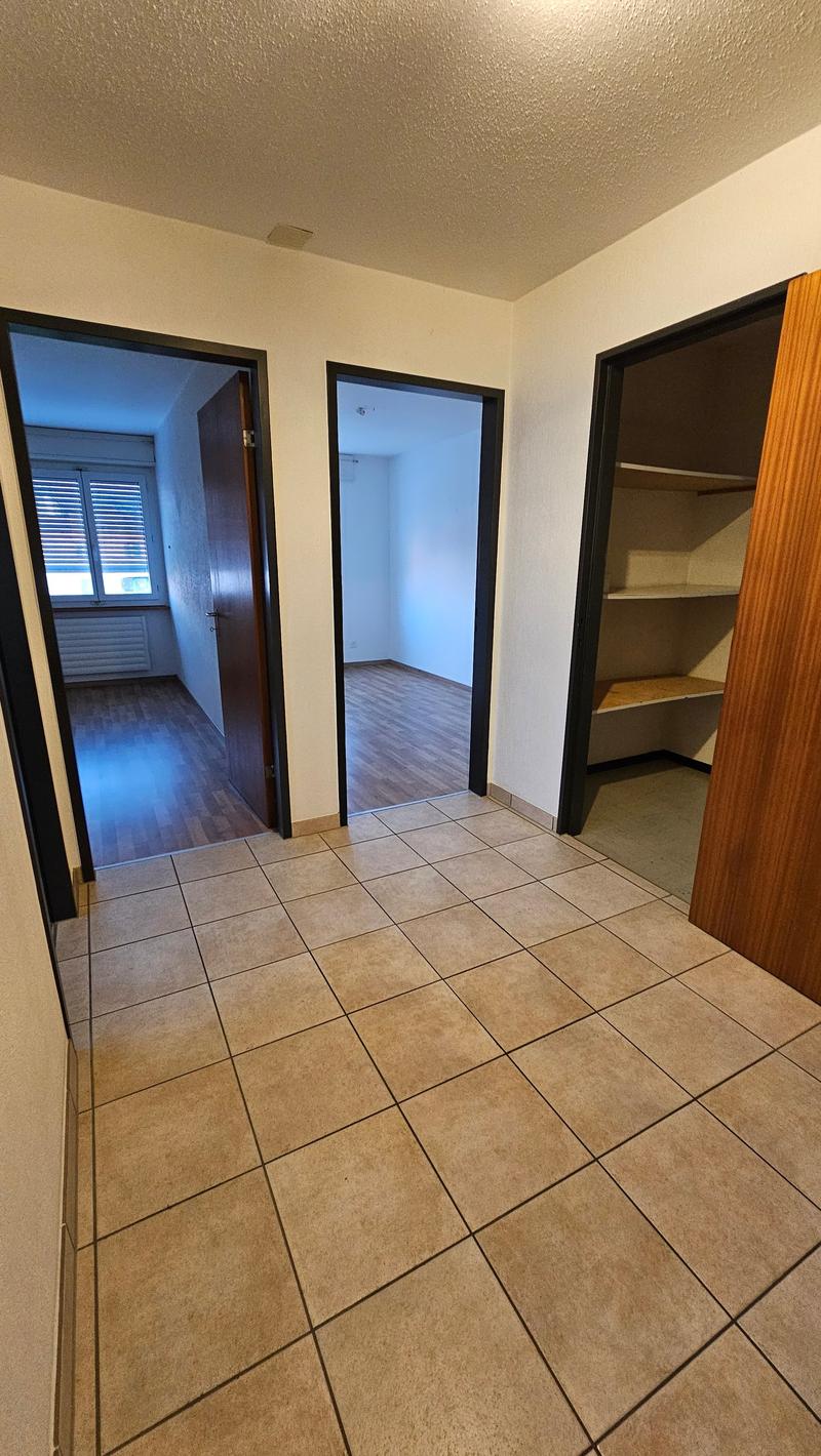 Empty room with tiled floor, three open doors, and a radiator in the left doorway.
