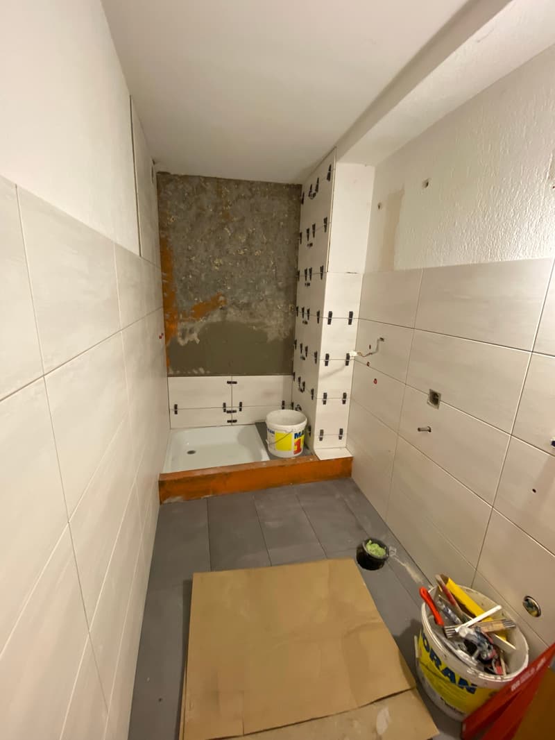 Bathroom under construction, white tiles, bathtub, buckets, tools
