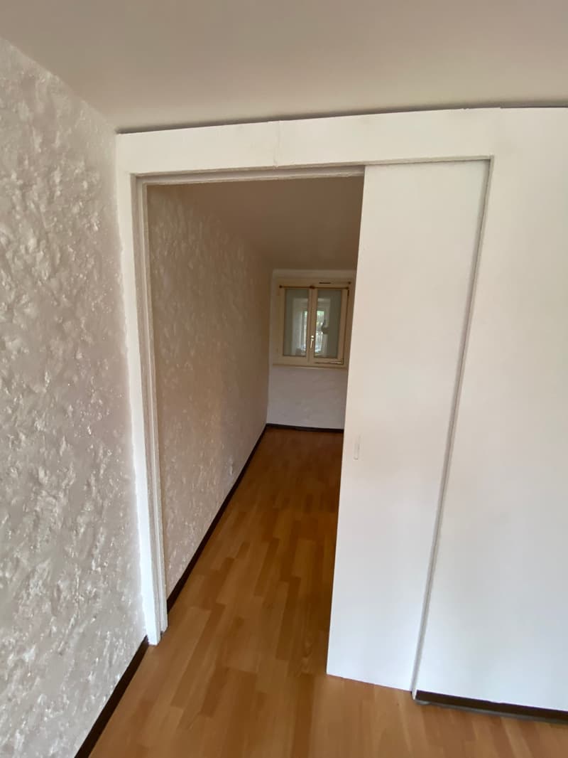 Empty room with wooden floor, white walls, and a window.