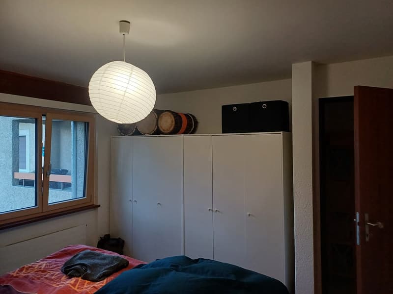 bedroom with bed, white wardrobe, drum set on top of wardrobe, lamp, window