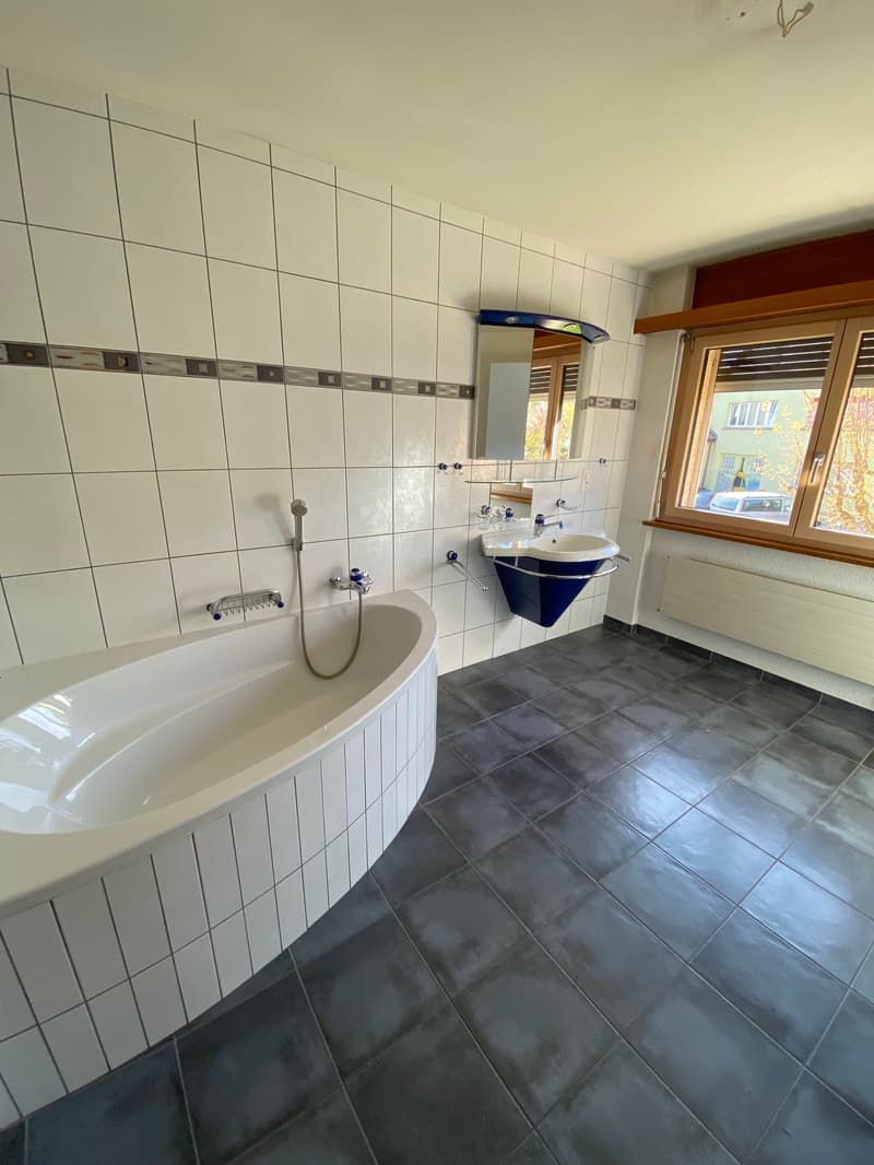 Bathroom with bathtub, sink, mirror, and window