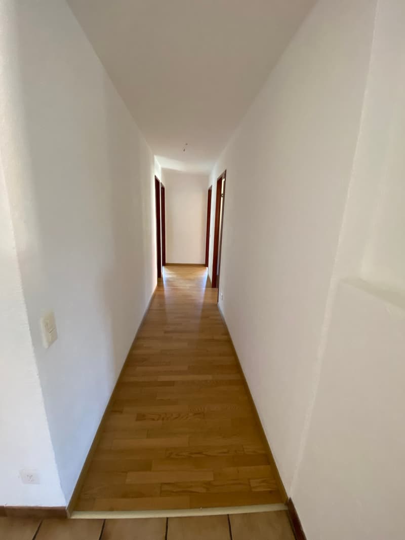 Empty hallway with wooden floor and white walls