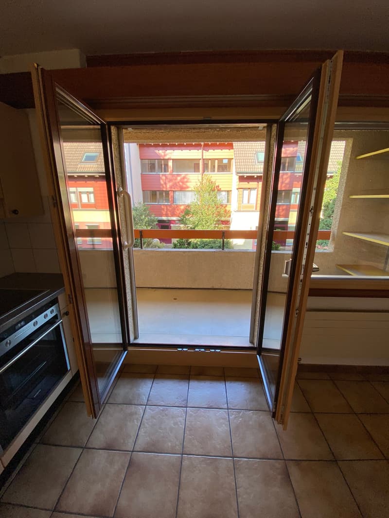 Open balcony doors, tiled floor, kitchen appliances, view of the building