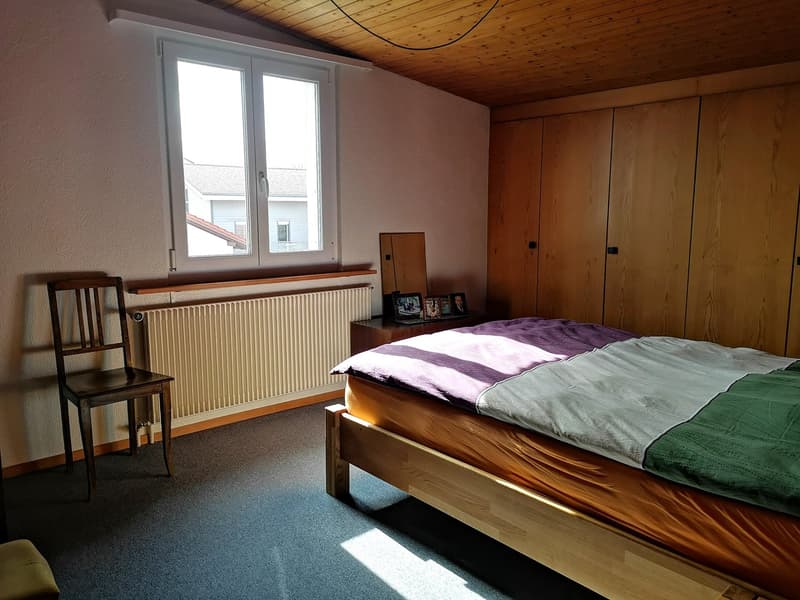 bedroom with bed, chair, radiator, wooden cabinet, window