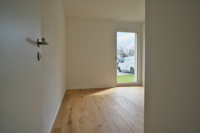 empty room, wooden floor, white walls, glass door, view of a grassy area and a van