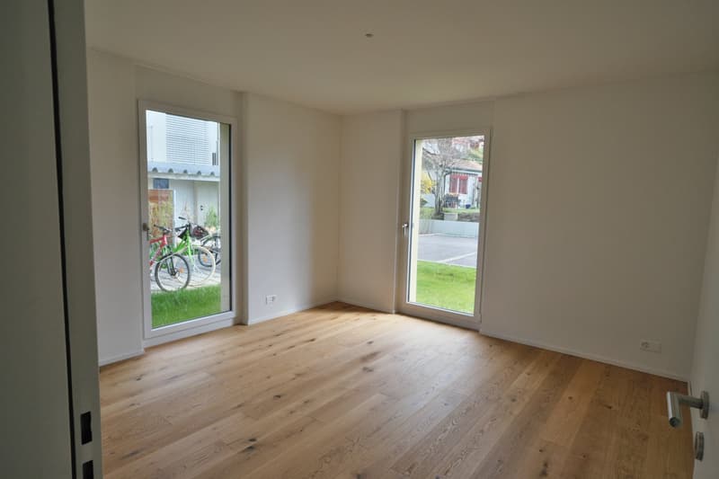 empty room, wooden floor, white walls, two glass doors, balcony with bicycles